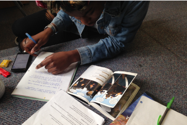 Young woman sitting on the floor doing homework with books and a notebook